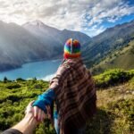 Woman overlooking mountains in Peru while the sun comes through the clouds and a beautiful lake is below (1)