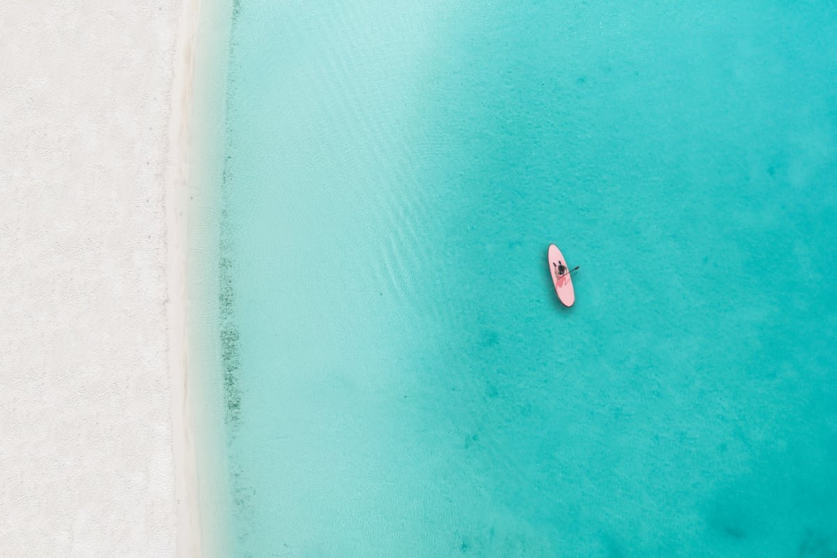 Drone photo of beach in Grace Bay, Providenciales, Turks and Caicos. The caribbean blue sea and underwater rocks can be seen, as well as some jet skies